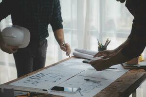 Close up of civil male engineer asian working on blueprint architectural project at construction site at desk in office. photo