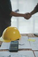 Close up of civil male engineer asian working on blueprint architectural project at construction site at desk in office. photo