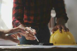 Close up of civil male engineer asian working on blueprint architectural project at construction site at desk in office. photo
