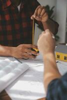 Close up of civil male engineer asian working on blueprint architectural project at construction site at desk in office. photo