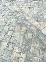 Old Stone Tiles. Tiled public space as parquet flooring, paving the street in gray colors. Old tiles on the ground. Abstract background with old stones. Textured gray background. Mosaic floor tiles photo