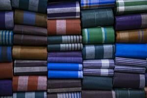 Multicolor Traditional Bangladeshi men's wear lungi folded on a rack in a store. Can be used as  pattern texture background wallpaper photo