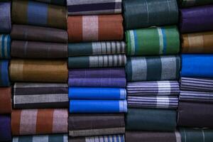 Multicolor Traditional Bangladeshi men's wear lungi folded on a rack in a store. Can be used as  pattern texture background wallpaper photo