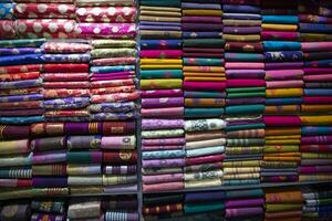 variedad artística colores de tono de sombra saris apilados en el estante de la tienda minorista para la venta foto