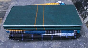 Folded Cotton Fabric Lungi on dark Concrete floor Traditional Men's Fashion Lifestyle in Bangladesh photo