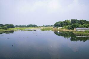 Reflection of trees in the lake water against the blue sky landscape countryside in Bangladesh photo