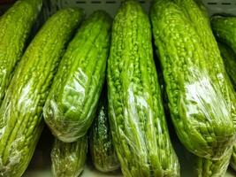 Pile of chinese bitter melon, Momordica charantia, for retail sale in Surakarta fresh food supermarket. Momordica charantia also known as balsam apple, balsam pear, bitter cucumber, bitter gourd. photo