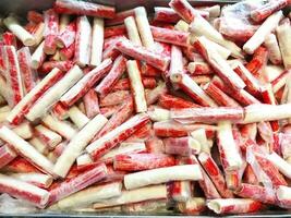 Pattern of bunch of Orange and white crab sticks in a supermarkets box photo