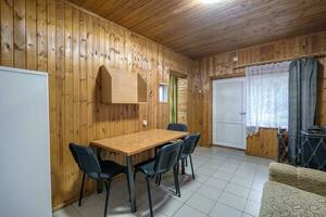 table with chairs and sofa in entrance hall of guestroom in wooden country eco house photo