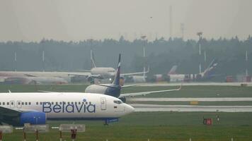 MOSCOW, RUSSIAN FEDERATION JULY 30, 2021 Boeing 737 of Belavia on the taxiway at Sheremetyevo airport, side view. Background, Aeroflot plane taking off video