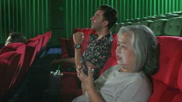 Senior mulher usando Móvel telefones dentro filme teatro perturba masculino hispânico e de outros audiências, mau maneiras comportamento quando assistindo filme shows, e estão irritado entretenimento estilo de vida com Smartphone. video