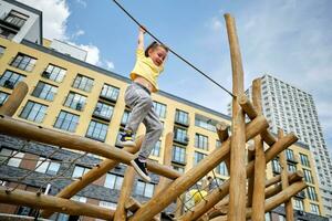 A girl hangs on a rope from a wooden sports complex. photo