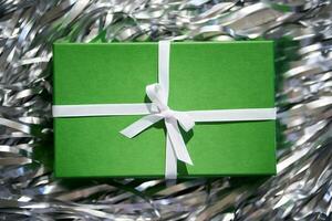 Green box with gifts on a gray background. photo
