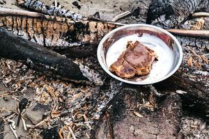 Steak in a tin plate on a fire. photo