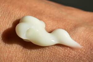 A smear of white moisturizer or sunscreen on a woman's hand. photo
