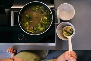 The girl serves the soup with a ladle. photo