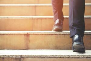 hombre de negocios moderno trabajando piernas de primer plano subiendo las escaleras en la ciudad moderna. en hora punta para trabajar en la oficina de prisa. durante la primera mañana de trabajo. escalera. enfoque suave. foto