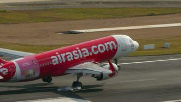 PHUKET, THAILAND FEBRUARY 19, 2023 Cinematic shot of passenger plane Airbus A320 of AirAsia landing, touching and braking at Phuket airport, sid eview. Low cost airline in Asia video