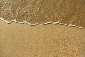 Close Up soft wave flow beautiful ocean on sandy beach. Background. sunshine in the evening. top view. photo