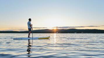 A man on a paddle board in the rays of sun. photo