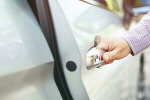 Close up image of a businessman hand on handle opening a car door. Pull the door to you. photo