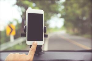 close up hand holding using mobile smart phone with black screen in car console front windshield holder stick. insert map gps navigation travel on the in the background of the dashboard. copy space. photo