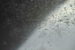 gotas de lluvia lloviznan en el parabrisas de cristal por la noche. calle bajo la fuerte lluvia. luz trasera bokeh. enfoque suave. por favor maneje con cuidado, camino resbaladizo. enfoque suave. foto