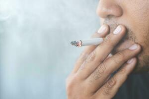 Close up young man smoking a cigarette. photo