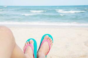 joven personas vestir el Zapatos sandalias de cerca pies dormido relajante en playa en arena disfrutando frío Dom en soleado verano día foto