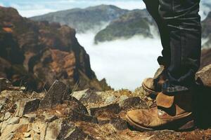 Traveler resting. Standing on a high mountain peak having enjoying wonderful breathtaking the forest mountain rocks view. Freedom travel concept. hiking shoes and man legs. photo