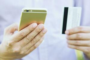 young male hands holding credit card and using phone sit order products and search information Online shopping purchase Sell or Payment. photo