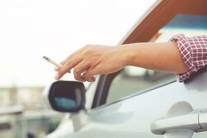 close up man hand hold smoking a cigarette in car while driving travel photo