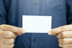 Man holding white business card on concrete wall background photo