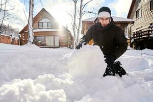 A family builds a snowman out of snow in the yard in winter. photo