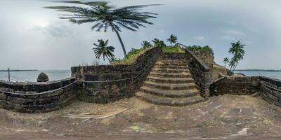 full hdri 360 panorama portuguese defensive abandoned military fortress with stone staircase on ocean with palm trees in equirectangular projection with zenith and nadir. VR AR content photo