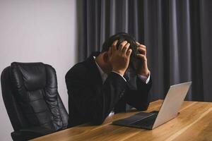 Businessman wearing black suit sitting stressed photo