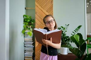 A school-age girl wearing glasses with books in hands. photo