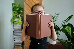 A school-age girl wearing glasses with books in hands. photo