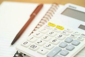 Money calculator and notebook,notepad,pen  on wood table, top view with copy space - financial background concept photo