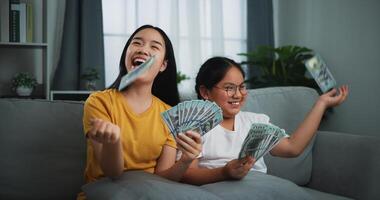 retrato de un joven mujer y Adolescente niña disfrutando dispersión efectivo cuentas en un sofá en el vivo habitación a hogar. foto