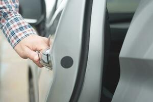 Close up image of a businessman hand on handle opening a car door. Pull the door to you. photo