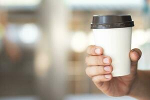 close up people young female hand holding paper cup of take away drinking coffee on natural morning sunlight sitting in public park. space Place for your text or logo. photo