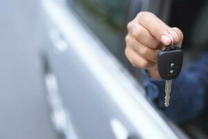 Car key, businessman handing over gives the car key to the other man on car parking background. photo