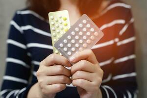 manos de mujer abriendo píldoras anticonceptivas en la mano. comiendo píldora anticonceptiva. foto