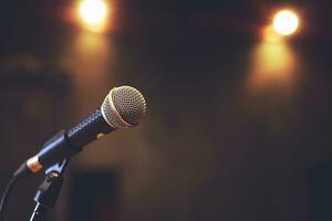 Close up of microphone on stage lighting at concert hall or conference room. copy space banner. soft focus. photo