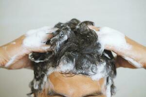 A man is washing his hair with shampoo photo