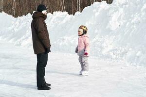 A girl in winter clothes learns to skate. photo