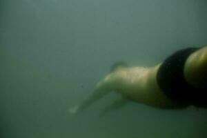 a man swimming in the ocean under water photo