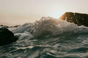 olas estrellarse en rocas a puesta de sol foto