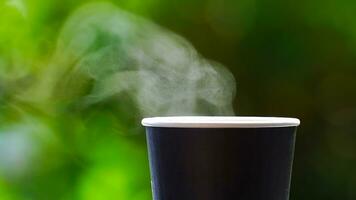 coffee takeaway in a paper cup on top of the car roof green tree background at sunrise in the morning,  selective focus, soft focus. photo